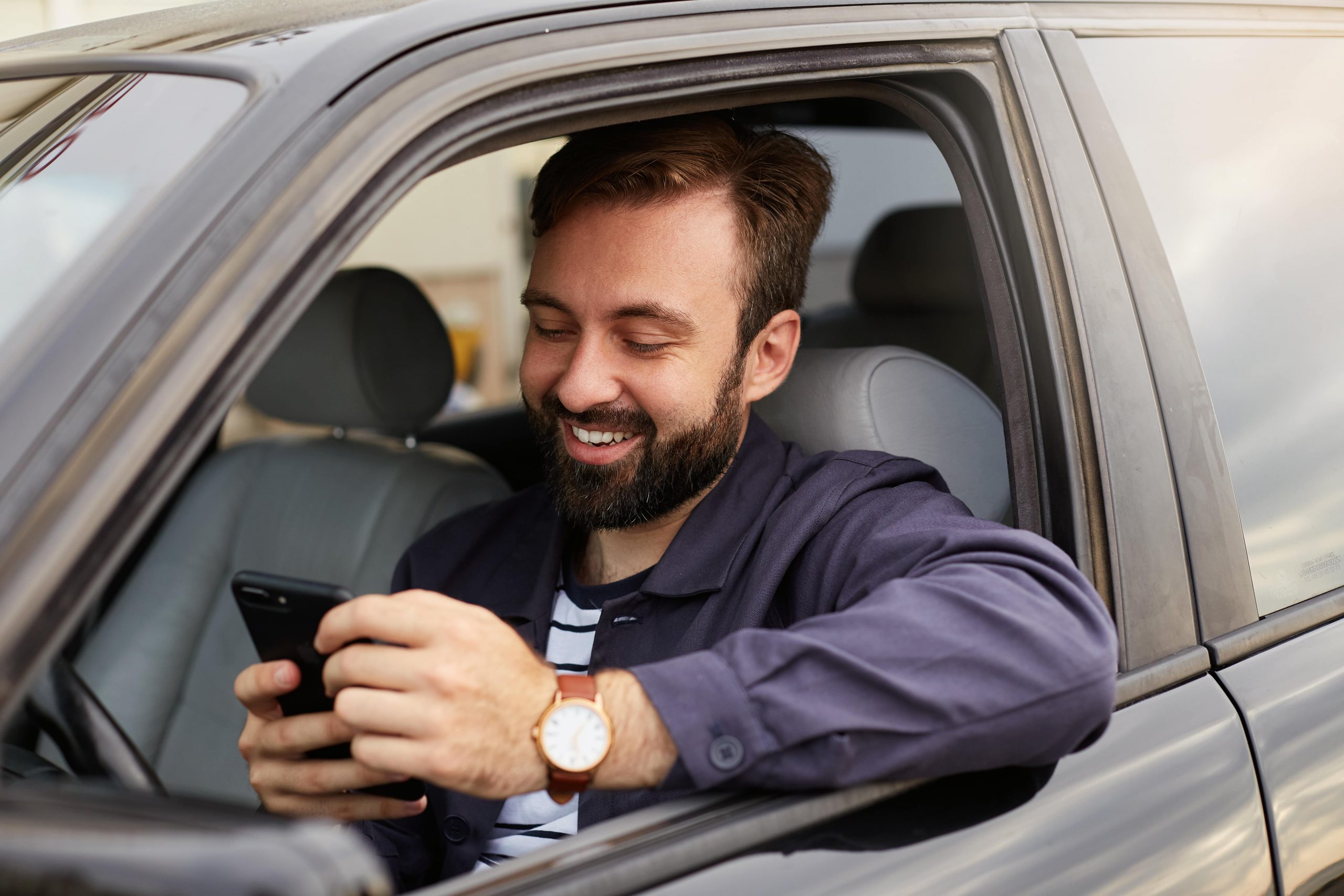 happy man using a mileage tracker app in car