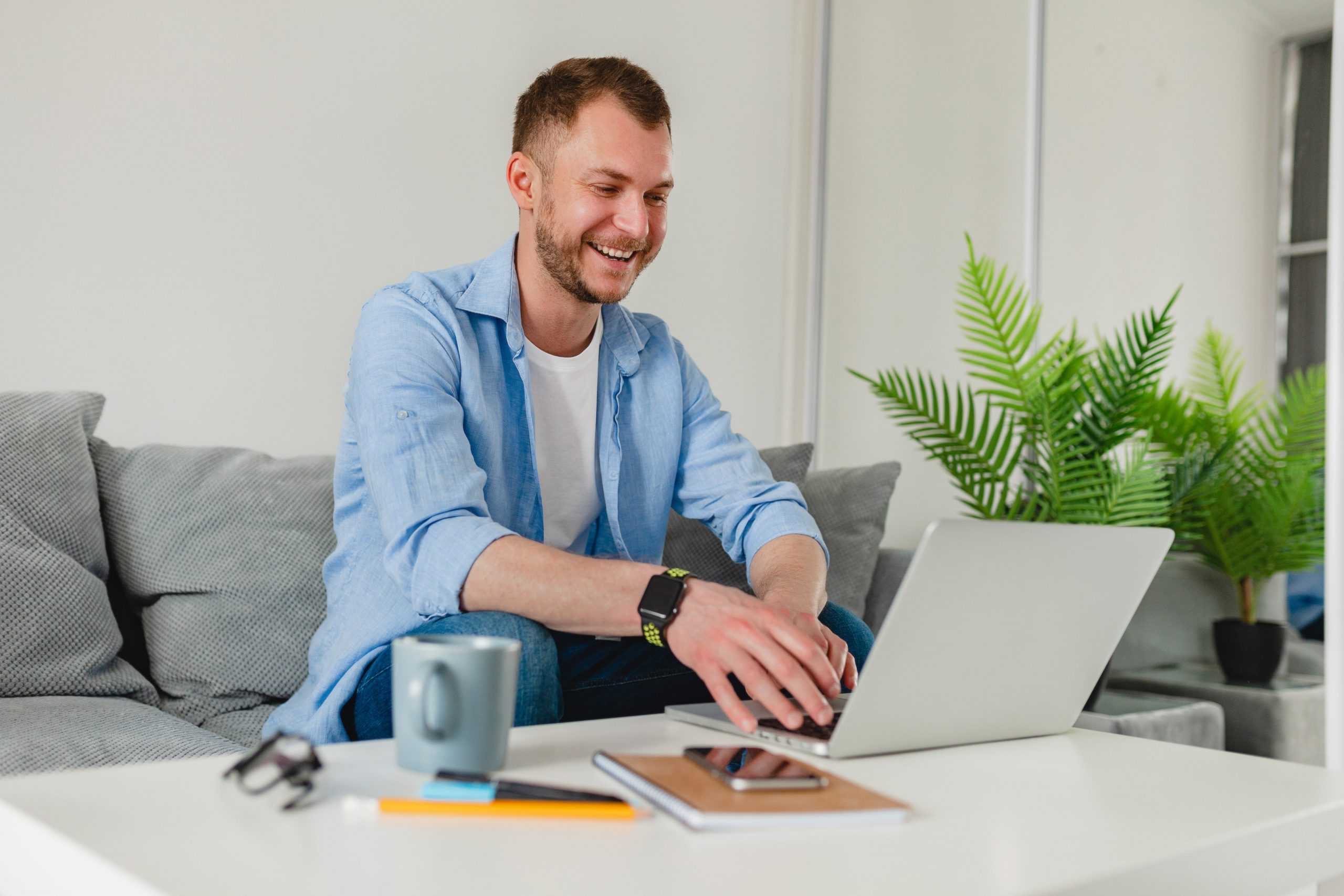 happy man creating a mileage log at home on laptop