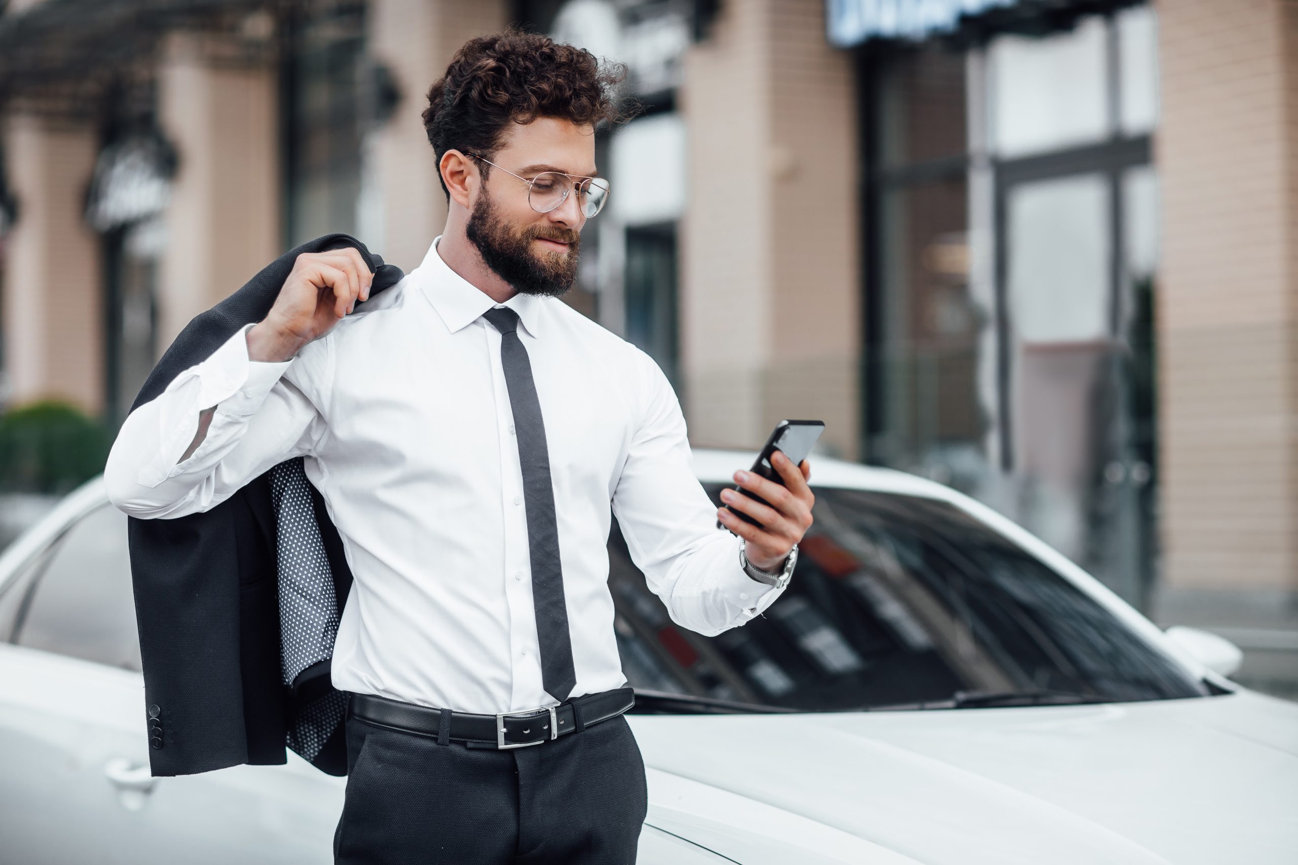 A man attentively reviewing his mileage records on his smartphone using an electronic mileage log tracking app.