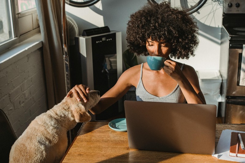 woman with dog sipping coffee, doing her mileage log