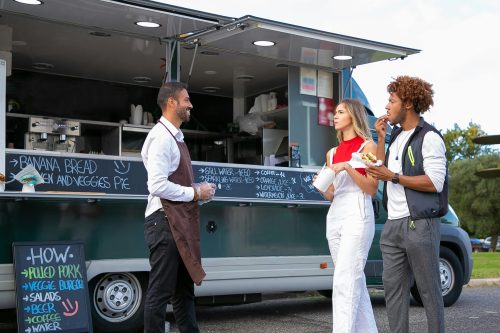 business van small business owner man discussing business with guests in front of a food truck